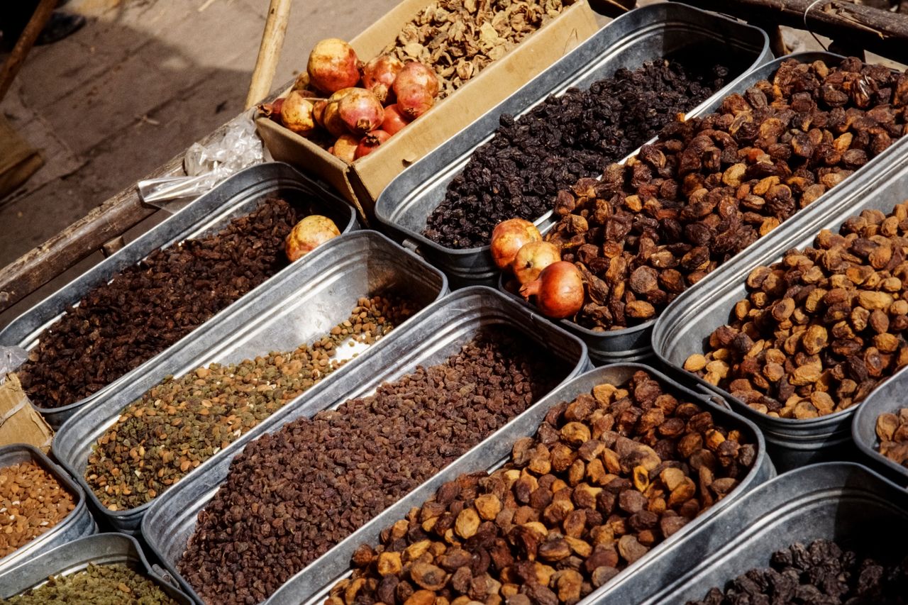 hero-img-02 A lively market stall in Pakistan offering a variety of dried fruits and spices, showcasing cultural richness.