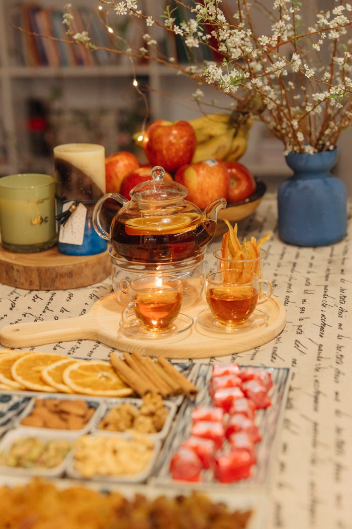 Warm indoor scene with tea, candles, and snacks on a table.
