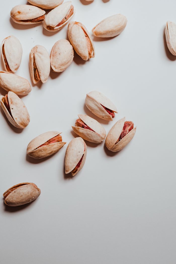 A flat lay of scattered pistachios on a clean white surface, showcasing their natural texture.