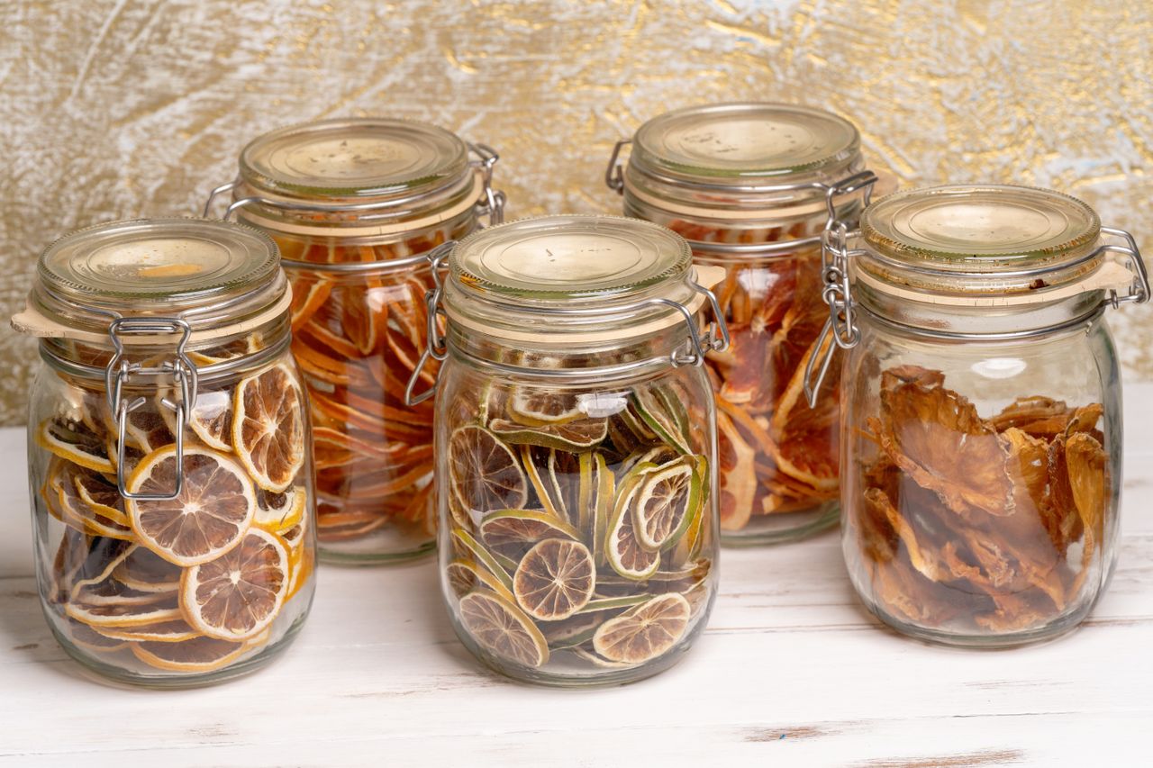 gallery-3 Colorful, preserved dried fruits arranged neatly in decorative glass jars on a white surface.